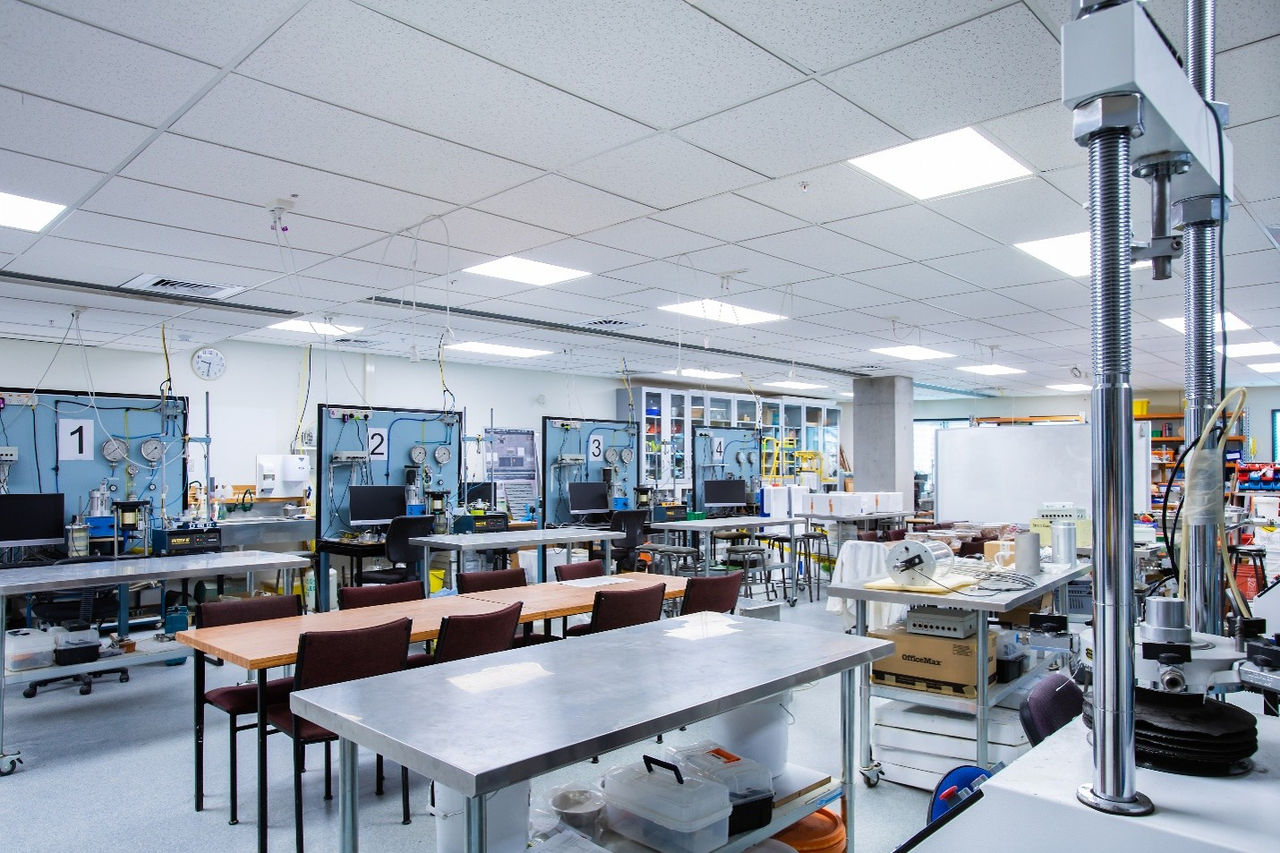 Long tables and chairs in the centre of the room, surrounded by geo testing workstations and equipment